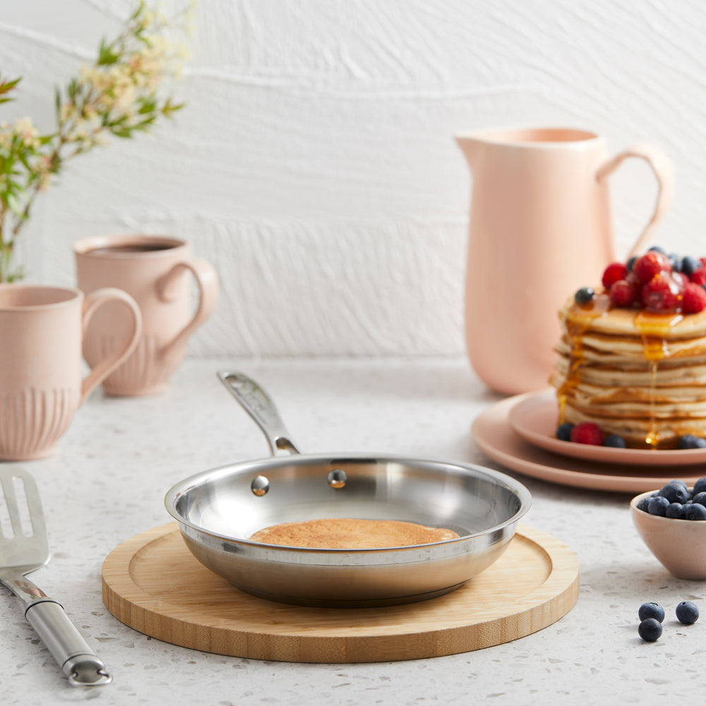 a steel pan on a wooden board with pastel tableware and pancakes with berries - Baccarat