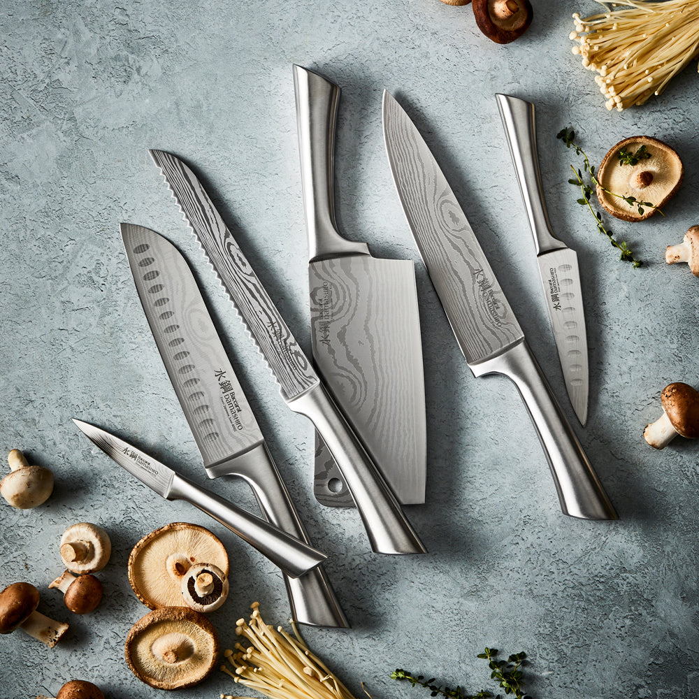 A Baccarat Damashiro cleaver with a sleek finish on a rustic surface surrounded by fresh ingredients