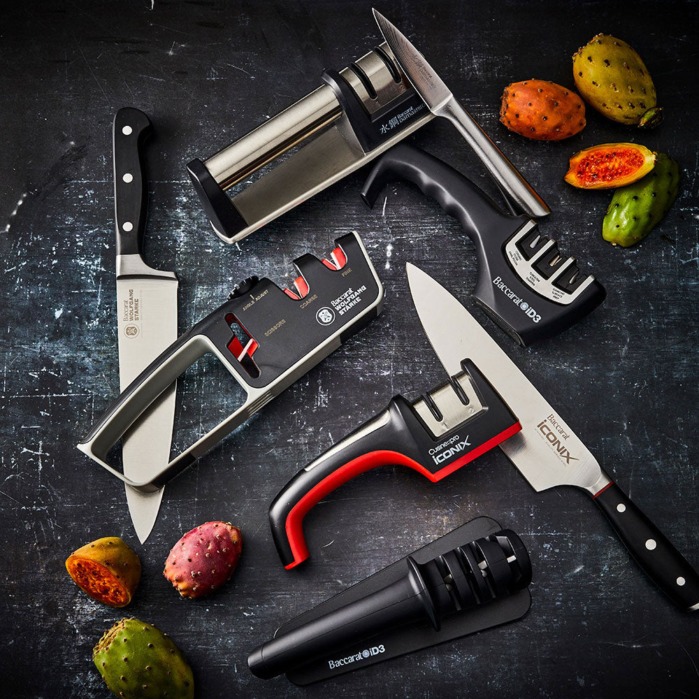 A person sharpens a large knife on a kitchen counter beside fruits- Baccarat 3-Step Knife Sharpener