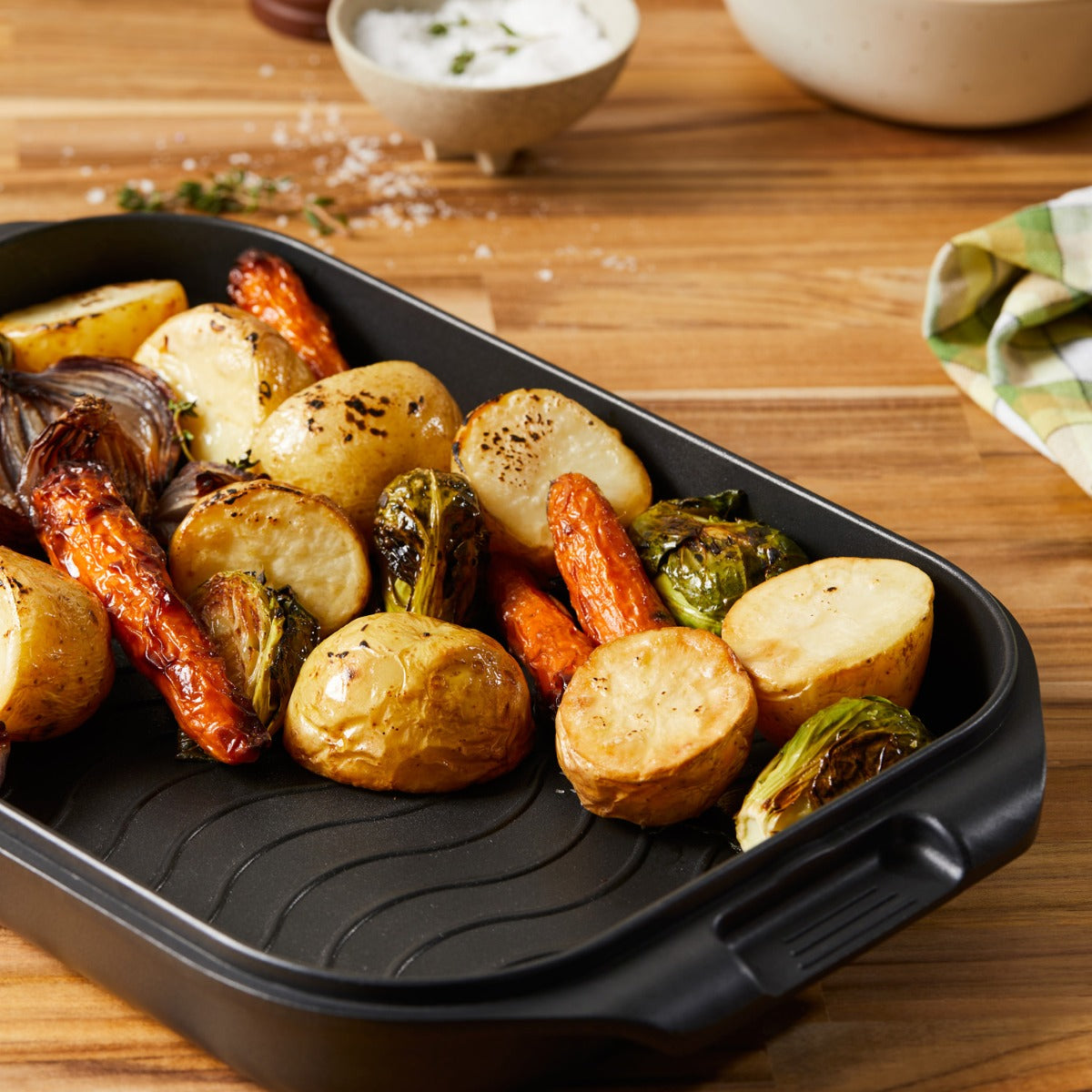 A roasted chicken with vegetables in a nonstick multi pan on a wooden table - Baccarat
