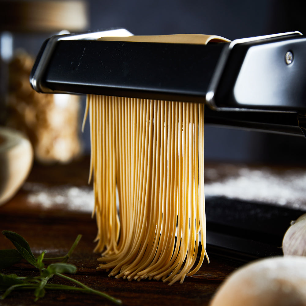 A person creating fresh golden pasta in a cozy kitchen - Baccarat gourmet 150mm pasta machine black