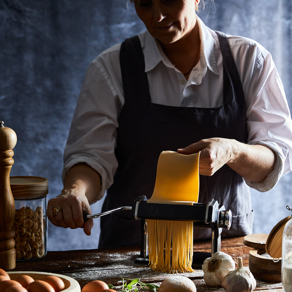 A person creating fresh golden pasta in a cozy kitchen - Baccarat gourmet 150mm pasta machine black