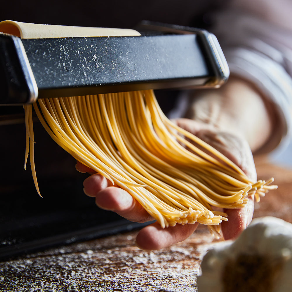A person creating fresh golden pasta in a cozy kitchen - Baccarat gourmet 150mm pasta machine black