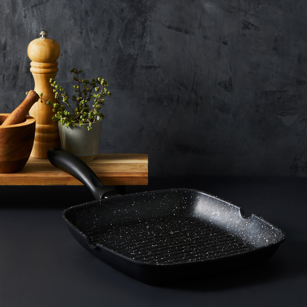 Person grilling corn with a black stone grill pan and spices nearby - Baccarat