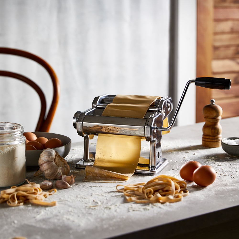 A pasta maker with fresh sheets and garlic on a table - silver pasta machine - Baccarat 150mm ii