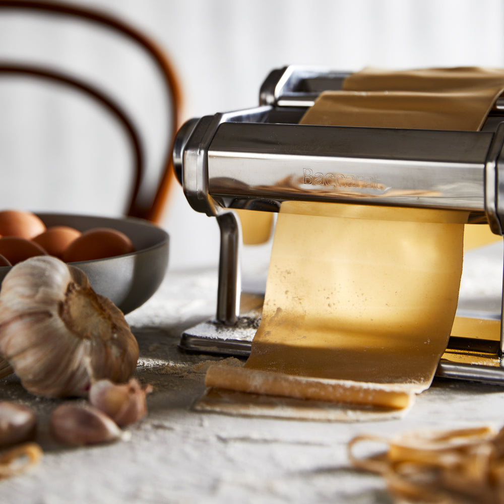 A pasta maker with fresh sheets and garlic on a table - silver pasta machine - Baccarat 150mm ii