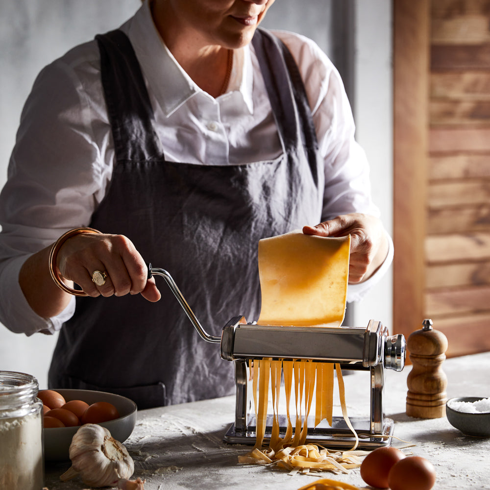 A pasta maker with fresh sheets and garlic on a table - silver pasta machine - Baccarat 150mm ii