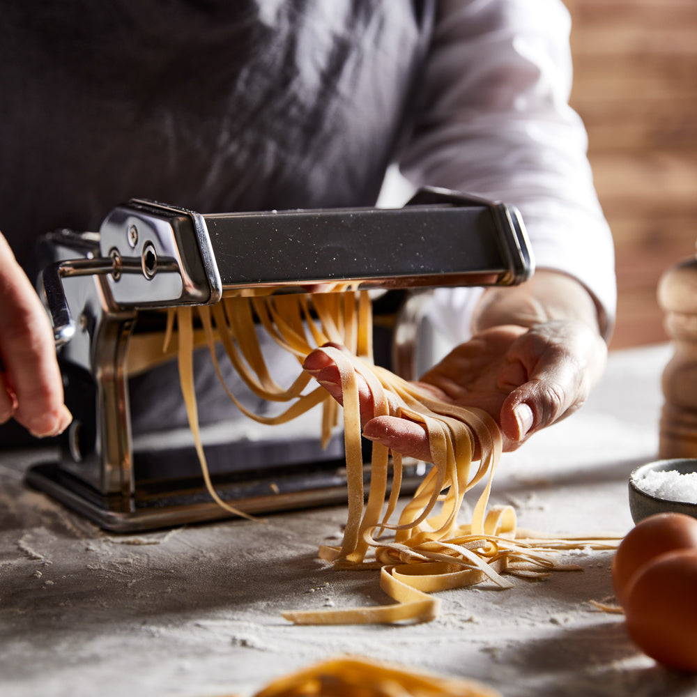 A pasta maker with fresh sheets and garlic on a table - silver pasta machine - Baccarat 150mm ii