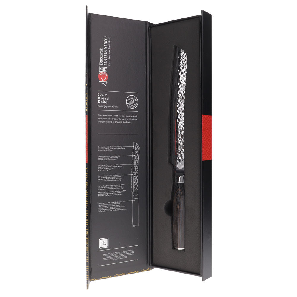 A Baccarat Emperor 20cm bread knife with a sharp edge on a wooden surface surrounded by other knives