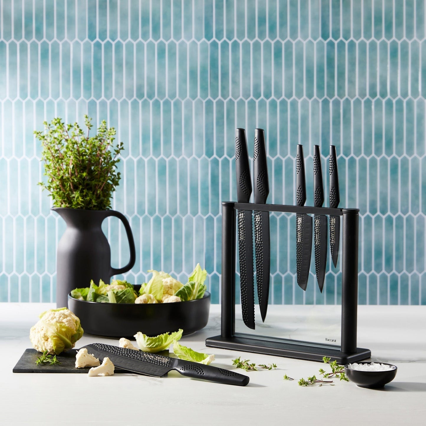 A person chops cabbage on a modern counter with a black knife block displaying knives - Baccarat