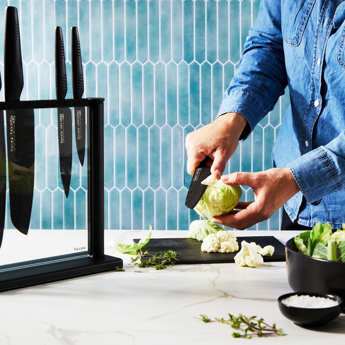 A person chops cabbage on a modern counter with a black knife block displaying knives - Baccarat