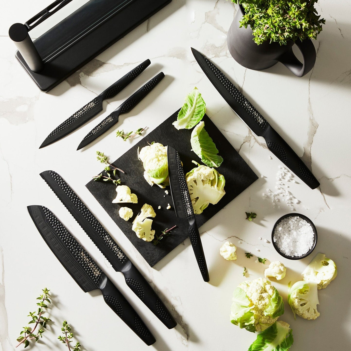 A person chops cabbage on a modern counter with a black knife block displaying knives - Baccarat
