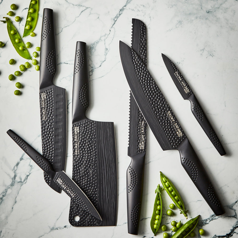 Six elegant Baccarat id3 Black Samurai Paring Knife 9cm arranged with green peas on marble