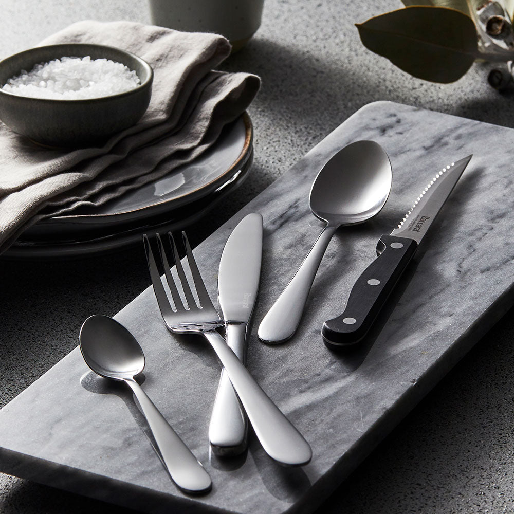 Elegant sabre Fussen 40 piece stainless cutlery set beautifully displayed on dark surface - Baccarat