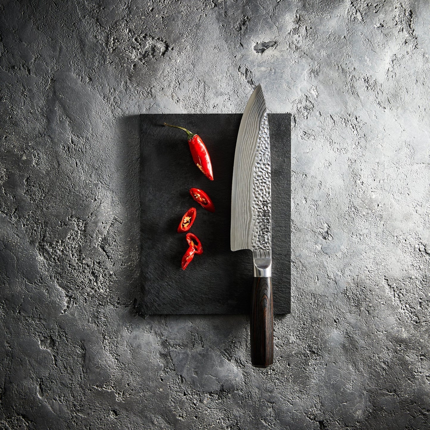 Sliced red peppers on a stone board with a sharp knife - Baccarat damashiro emperor chefs knife 20cm