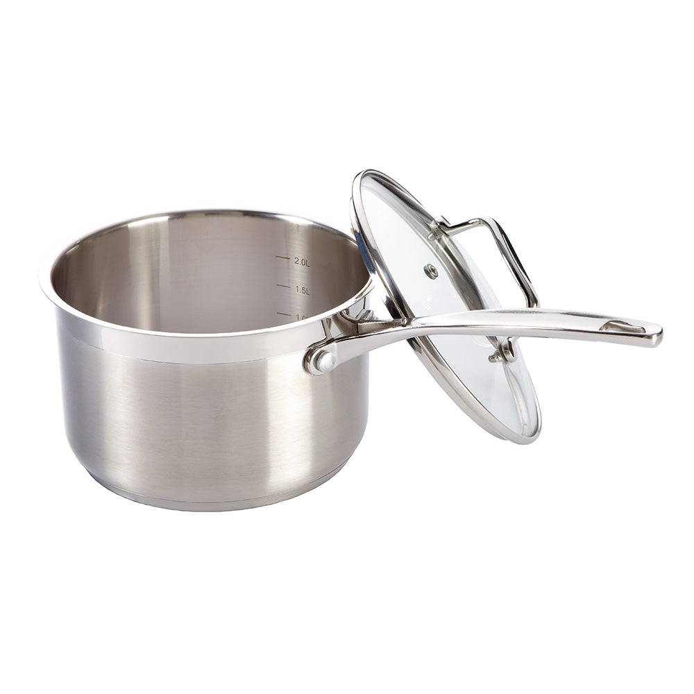 A hand pours pasta into a Baccarat iconix saucepan with lid 18cm on a wooden board - Baccarat