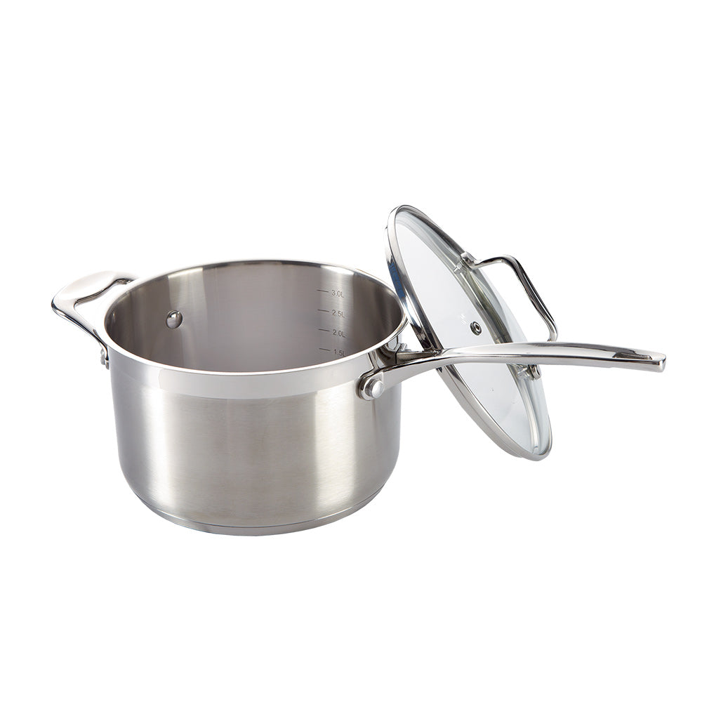 Pasta being poured into a saucepan on a wooden surface with an olive oil bottle - Baccarat