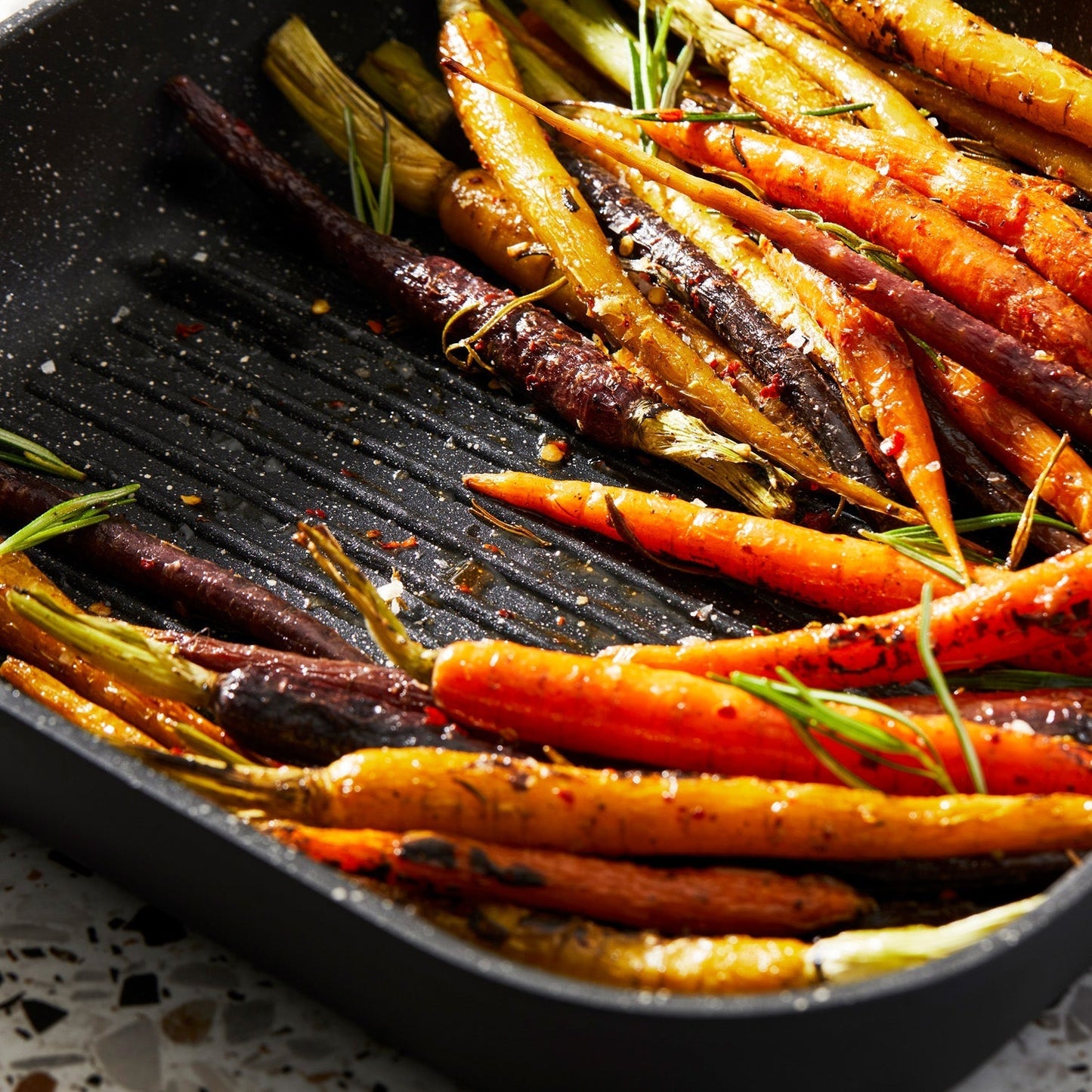 Grilled vibrant rainbow carrots in a sleek black pan - Baccarat granite grill pan 28cm - brand