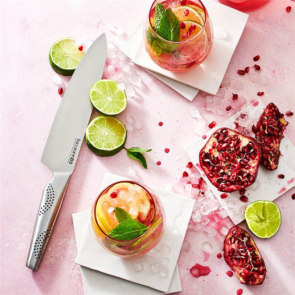 Top view of vibrant lime and pomegranate drinks with a sleek knife on a pink surface - Baccarat