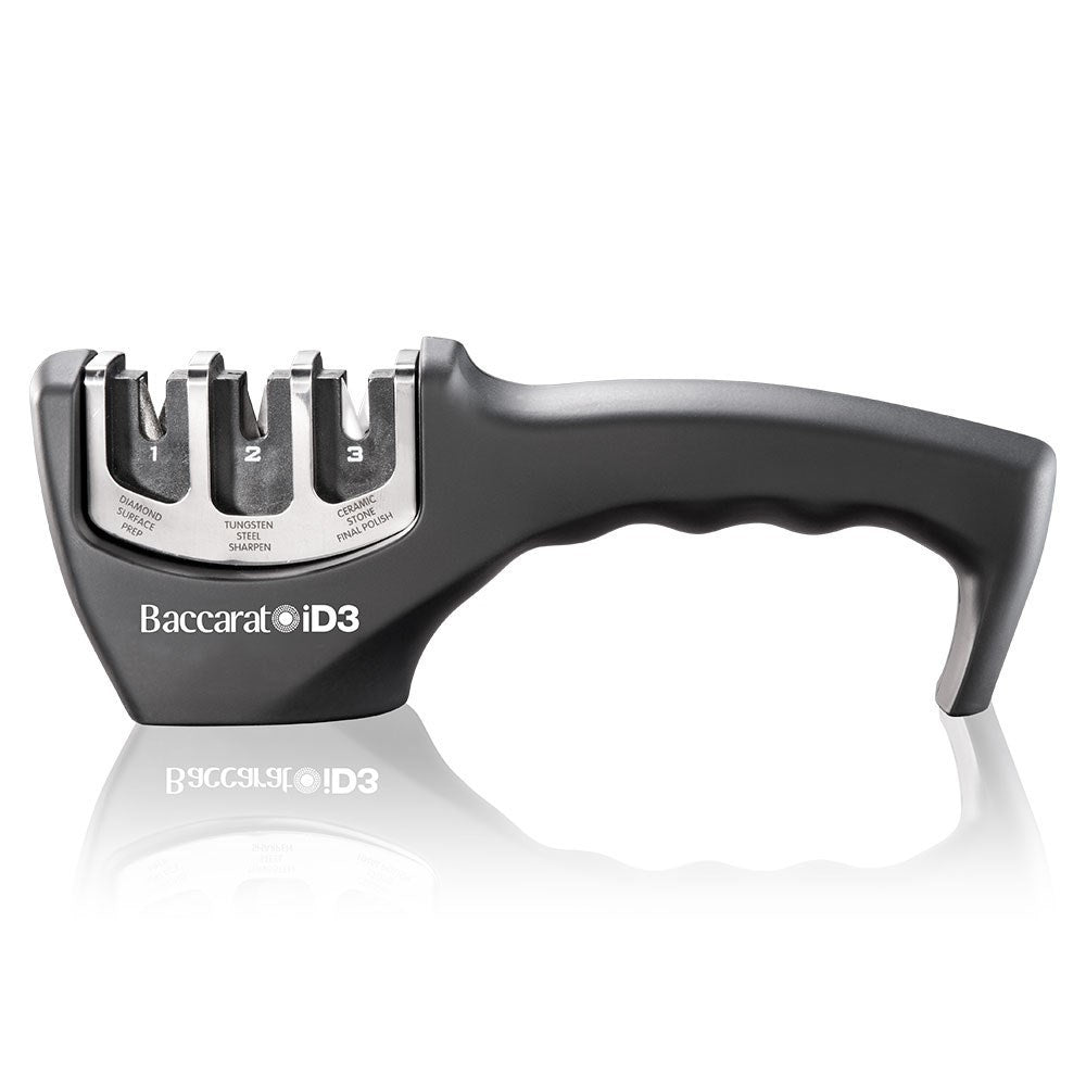 A person sharpens a large knife on a kitchen counter beside fruits- Baccarat 3-Step Knife Sharpener