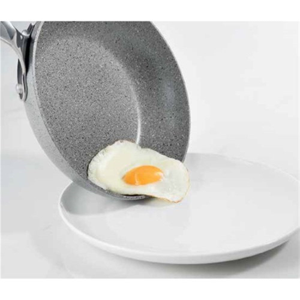 A fried egg is effortlessly slid onto a plate from a frying pan - grey non-stick cookware - Baccarat
