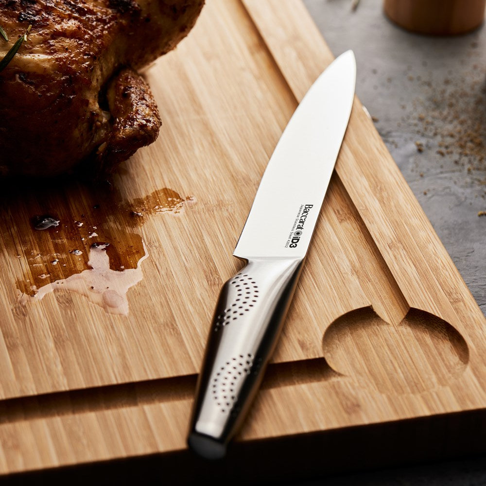 Person carving a roasted chicken on a wooden board with a smooth cutting edge - Baccarat ID3