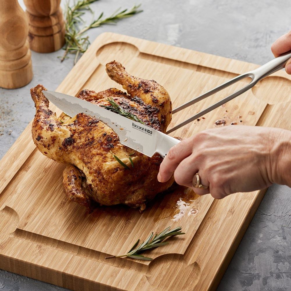 Person carving a roasted chicken on a wooden board with a smooth cutting edge - Baccarat ID3