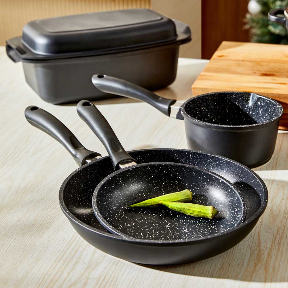 A modern kitchen featuring a sleek stir fry pan and cookware set in stone finish - Baccarat