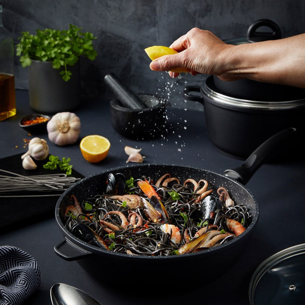 A pan of seafood pasta is topped with fresh lemon juice glistening in the sunlight - Baccarat
