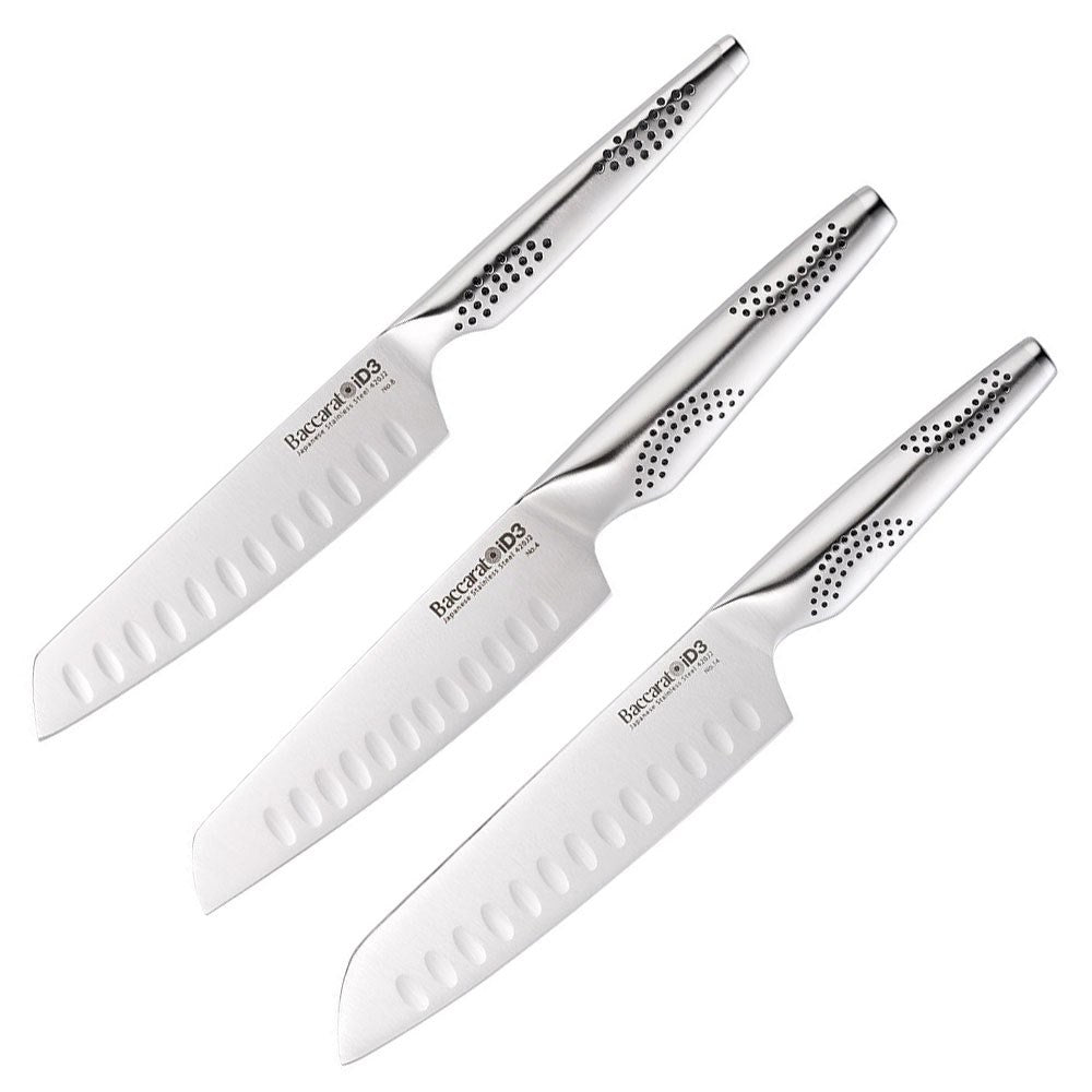 Three santoku knives resting on a wooden cutting board with fresh herbs and vegetables - Baccarat