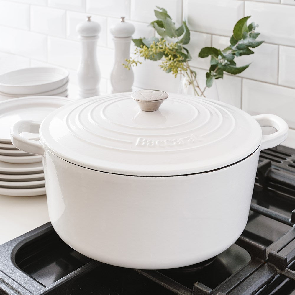 Black cast iron round French oven on stovetop with plates and greenery - Baccarat Le Connoisseur