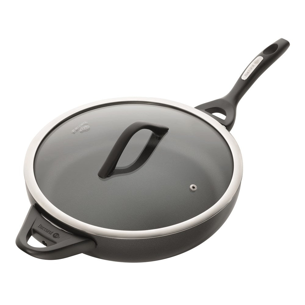 A sauté pan with chopped onions and green vegetables on a striped cloth - Baccarat