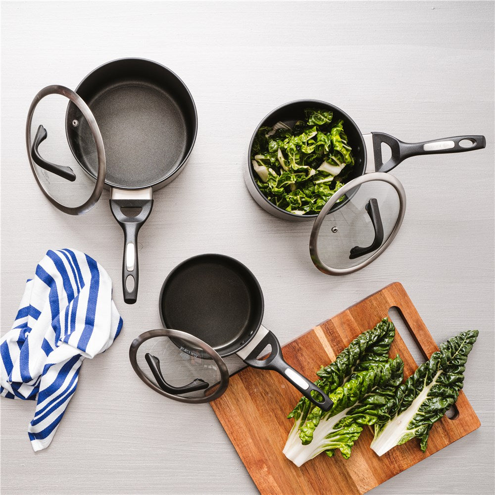 Hard anodised saucepan with lid and bakelite handle vegetables on gray surface - Baccarat