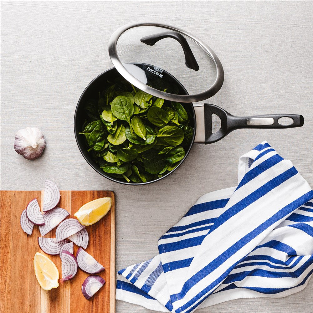 Hard anodised saucepan with lid and bakelite handle vegetables on gray surface - Baccarat