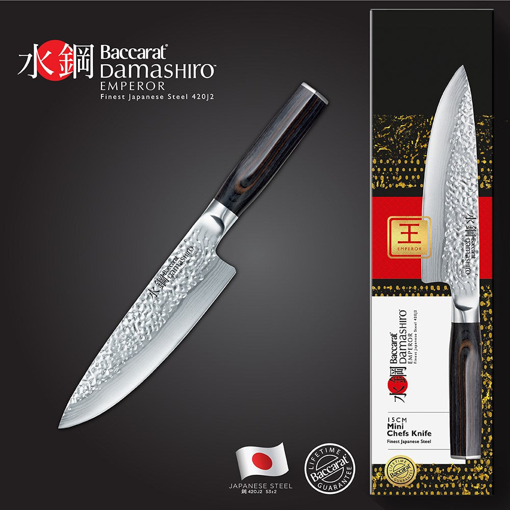 A stunning Baccarat Damashiro Emperor 15 cm chef's knife on a dark cutting board with green veggies