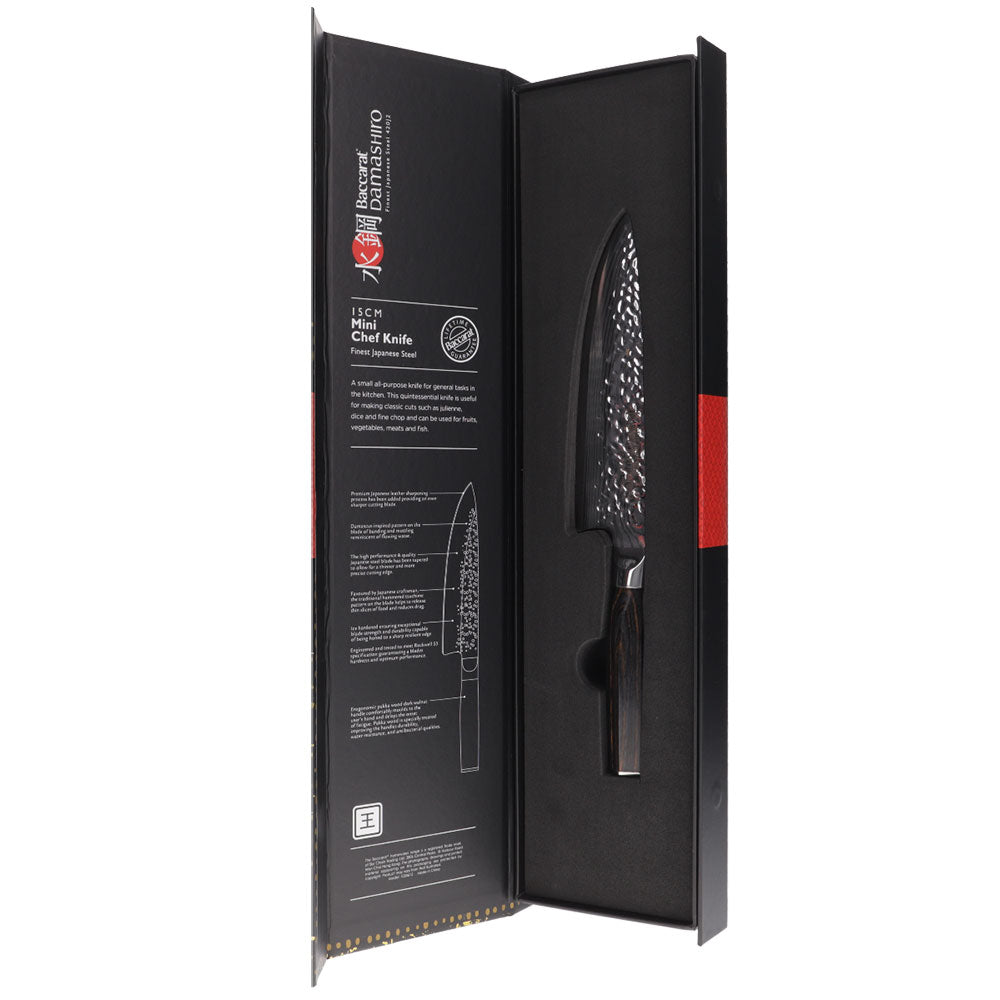 A stunning Baccarat Damashiro Emperor 15 cm chef's knife on a dark cutting board with green veggies