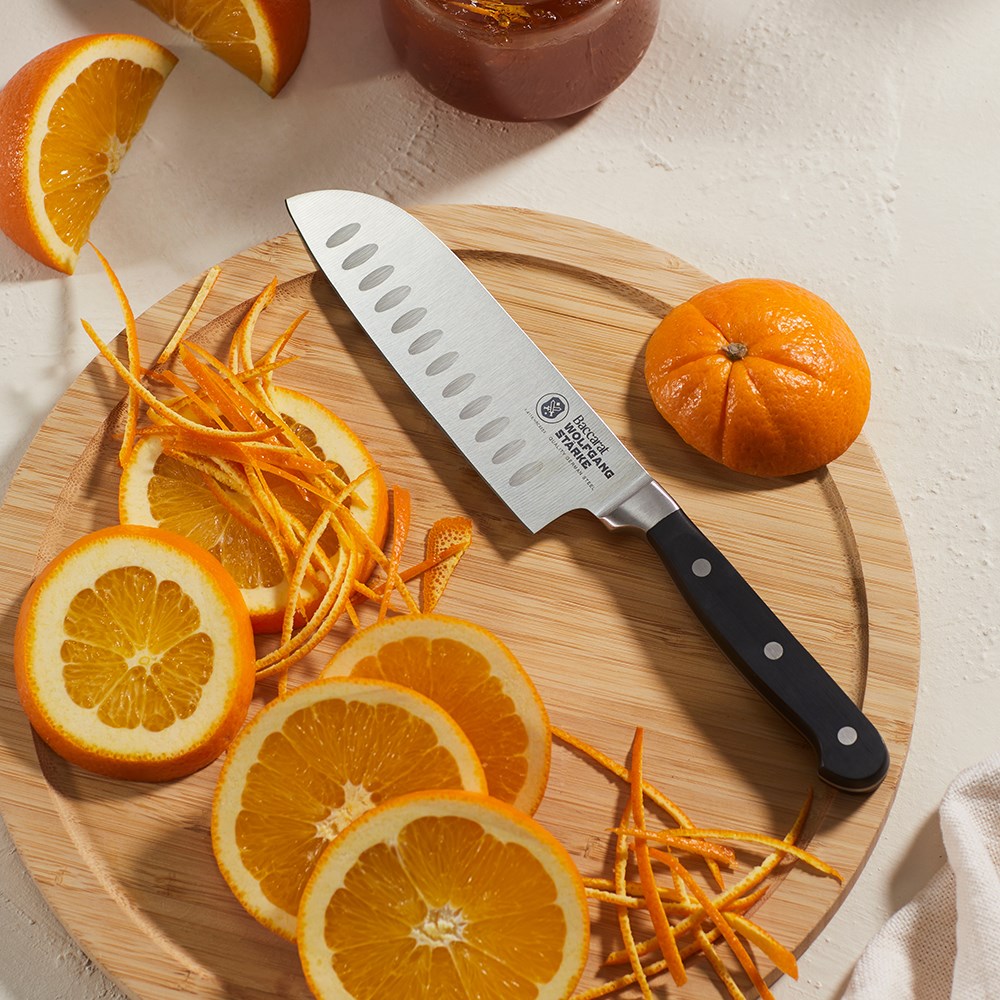 A stainless steel chefs knife with a black handle and sleek design - Baccarat Wolfgang Starke