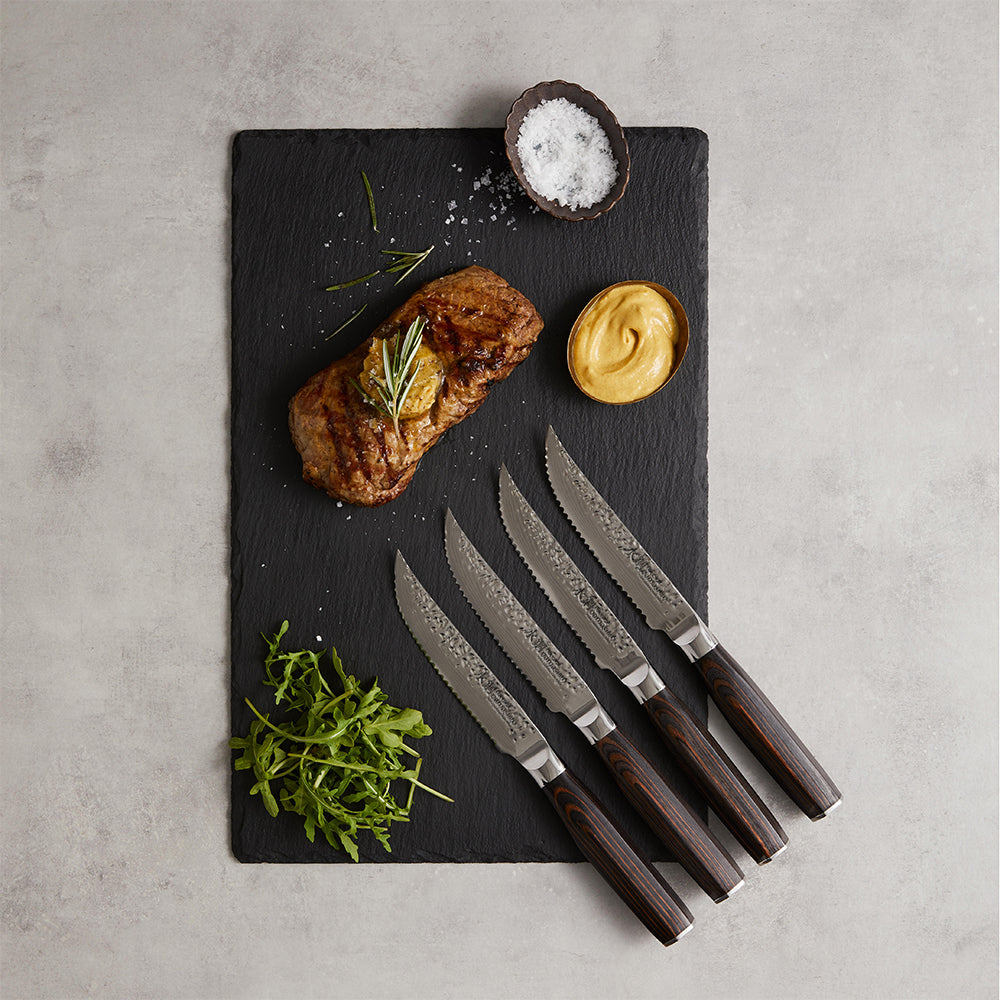 Marbled tomahawk steak with four elegant knives on a dark stone surface - Baccarat damashiro emperor