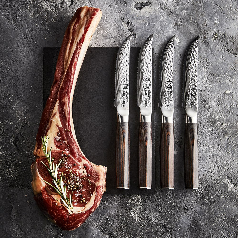 Marbled tomahawk steak with four elegant knives on a dark stone surface - Baccarat damashiro emperor