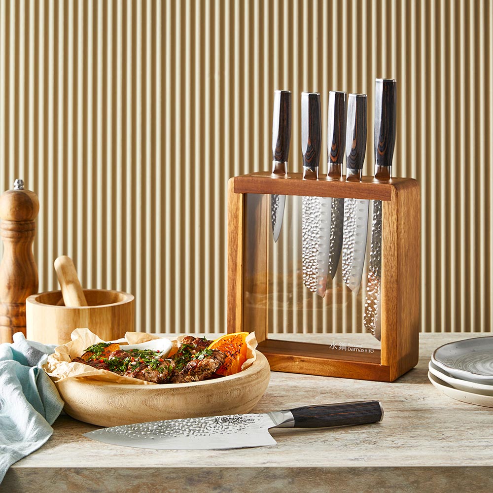 Seven sleek knives in a stylish wooden block on a countertop gleaming in light - Baccarat damashiro
