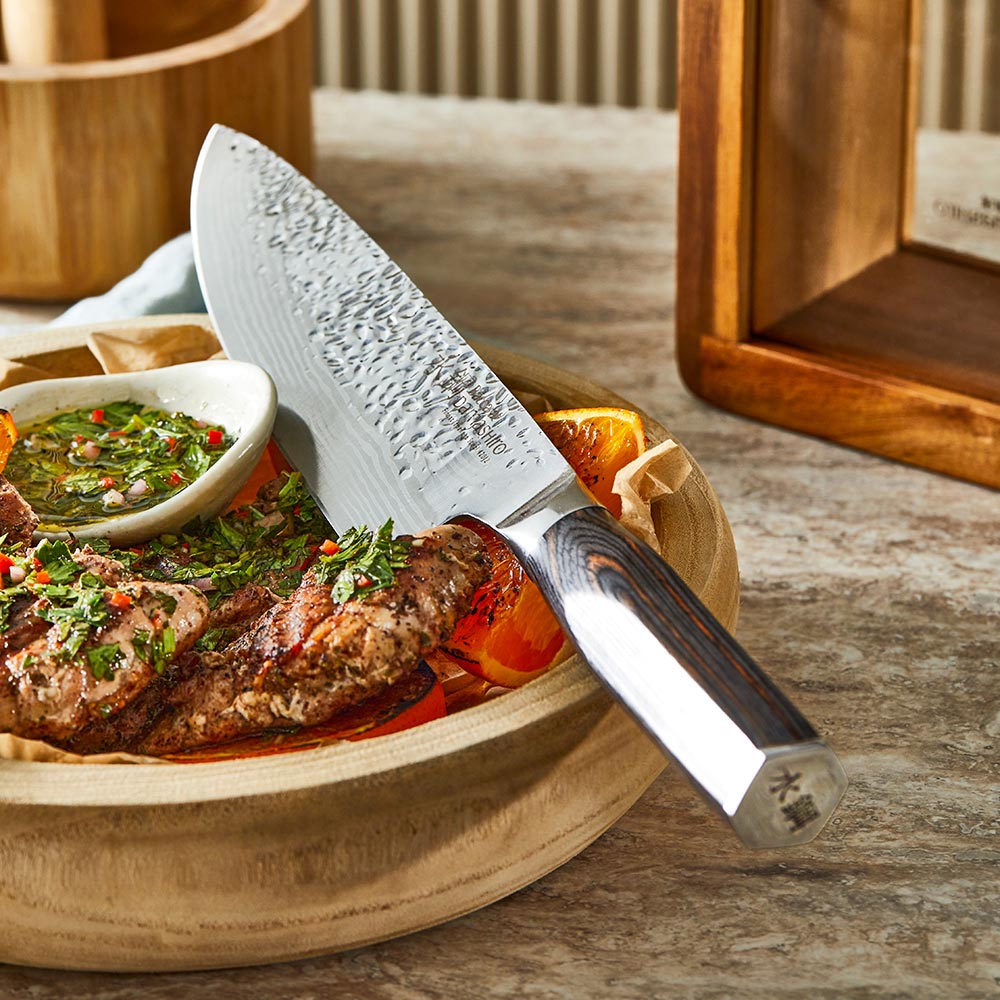 Seven sleek knives in a stylish wooden block on a countertop gleaming in light - Baccarat damashiro