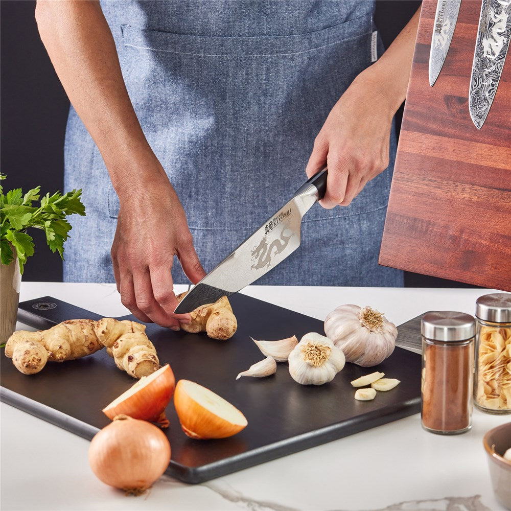 Person chopping ginger and garlic on black cutting board with black Samurai cleaver knife - Baccarat