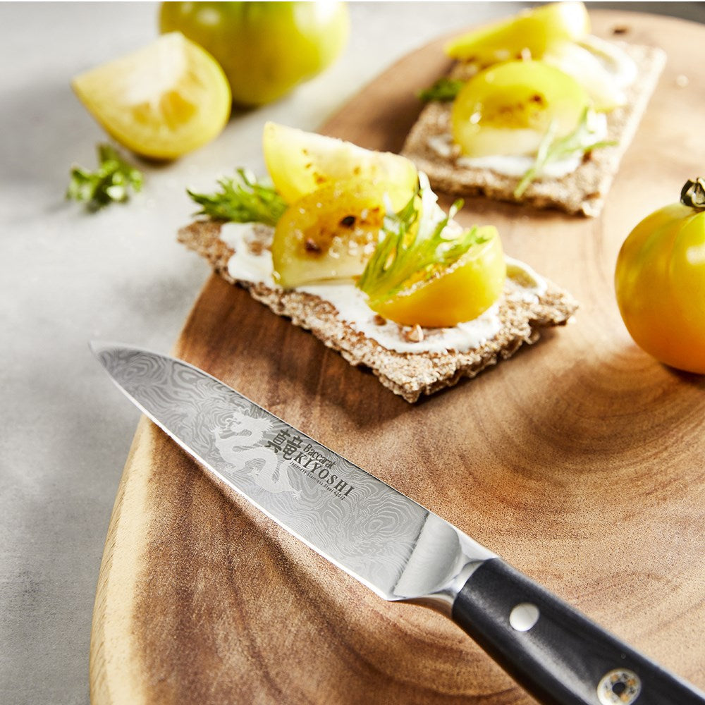 A wooden board with green tomatoes and crackers alongside a knife and pepper grinder set - Baccarat