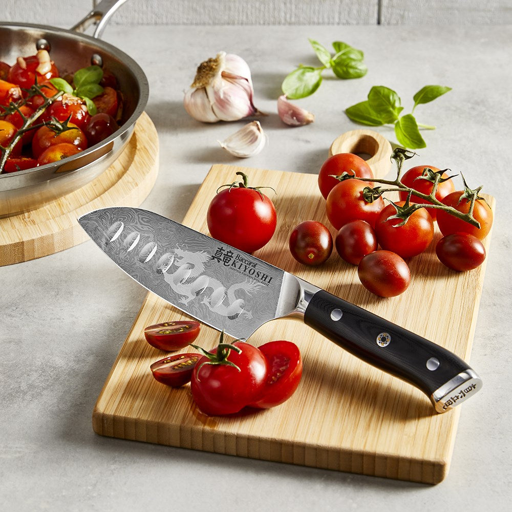 Fresh tomatoes and a garlic clove on a wooden cutting board with a santoku knife - Baccarat kiyoshi