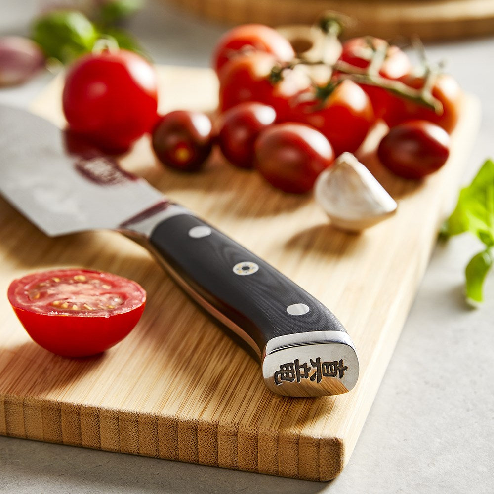 Fresh tomatoes and a garlic clove on a wooden cutting board with a santoku knife - Baccarat kiyoshi