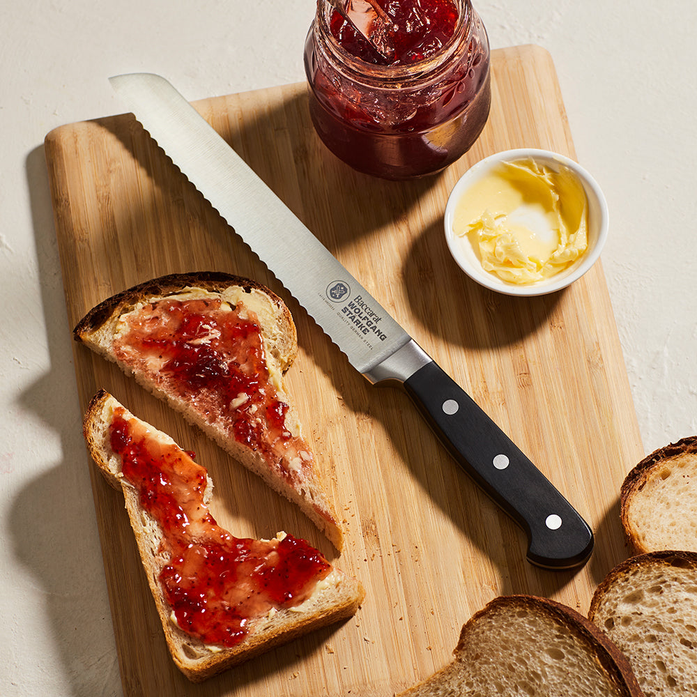 A serrated bread knife with a black ergonomic handle and silver blade ideal for slicing - Baccarat