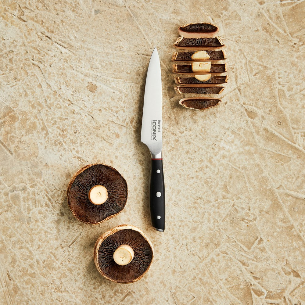 A sleek silver kitchen knife on a dark slate background black handle utility knife 12 5cm - Iconix