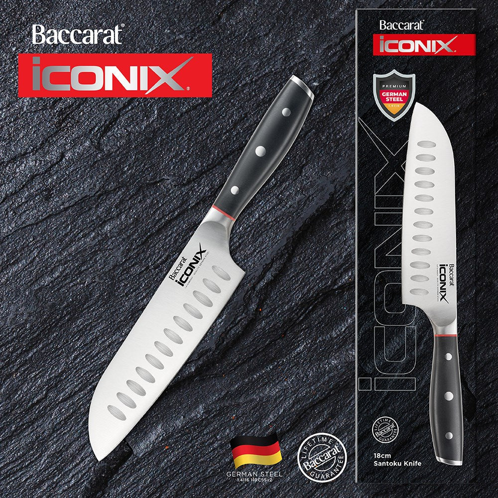 A sleek Baccarat Iconix Santoku Knife with a black handle and silver blade beside its packaging
