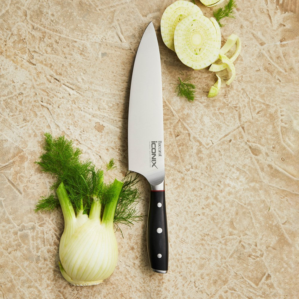 A person chops fennel on a beige countertop green shirt cutting board santoku knife 18cm - Iconix