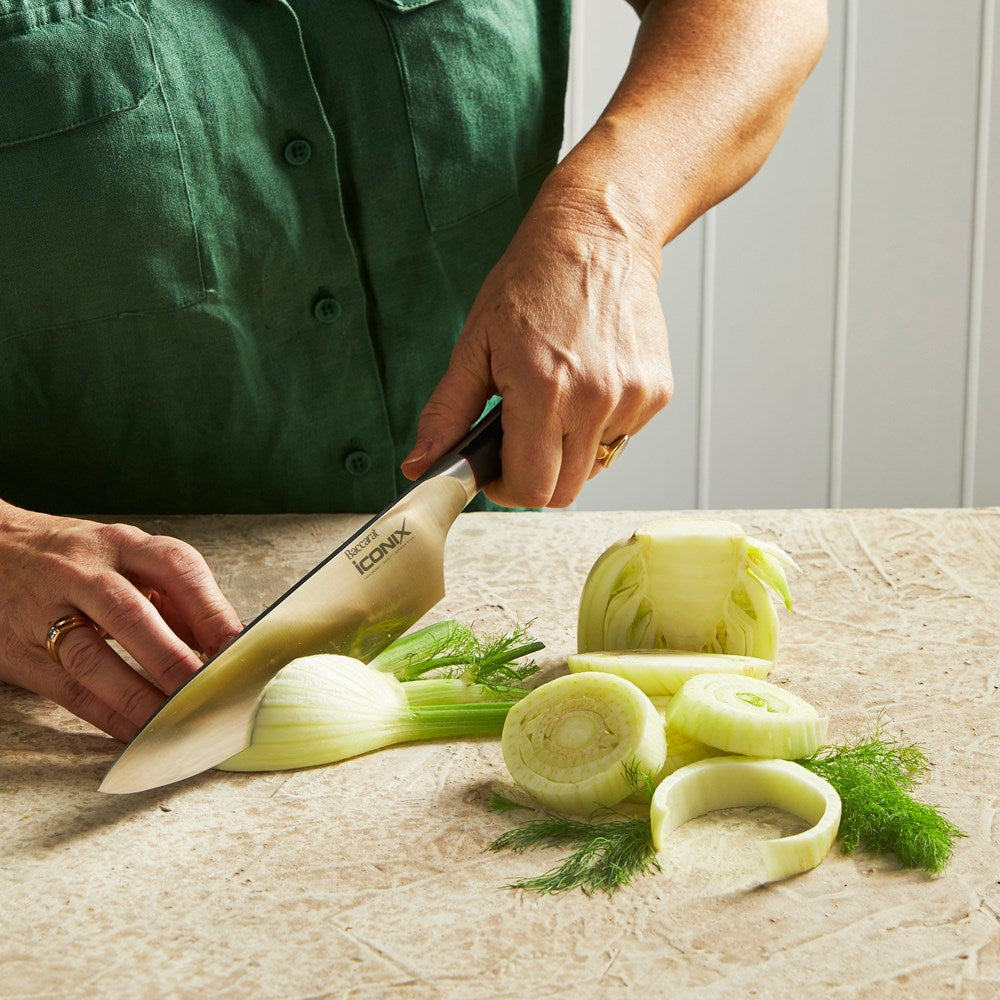 A person chops fennel on a beige countertop green shirt cutting board santoku knife 18cm - Iconix